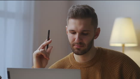 man-is-communicating-by-video-call-on-laptop-listening-and-answering-portrait-in-room-working-from-home-remote-communication-of-colleagues